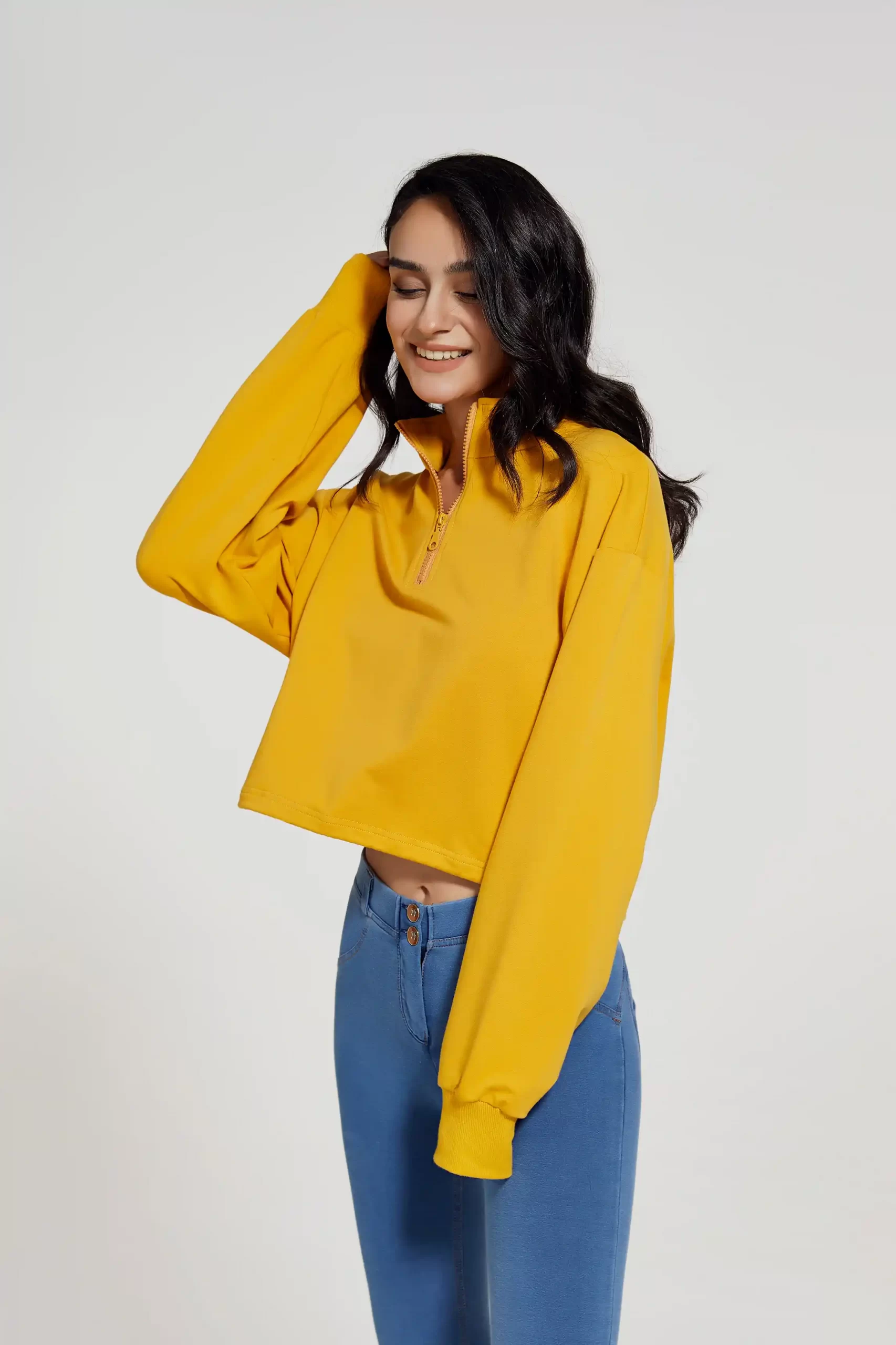 Activewear model posing in relaxed yellow pullover and form-fitting high waist leggings, perfect for fitness and athleisure