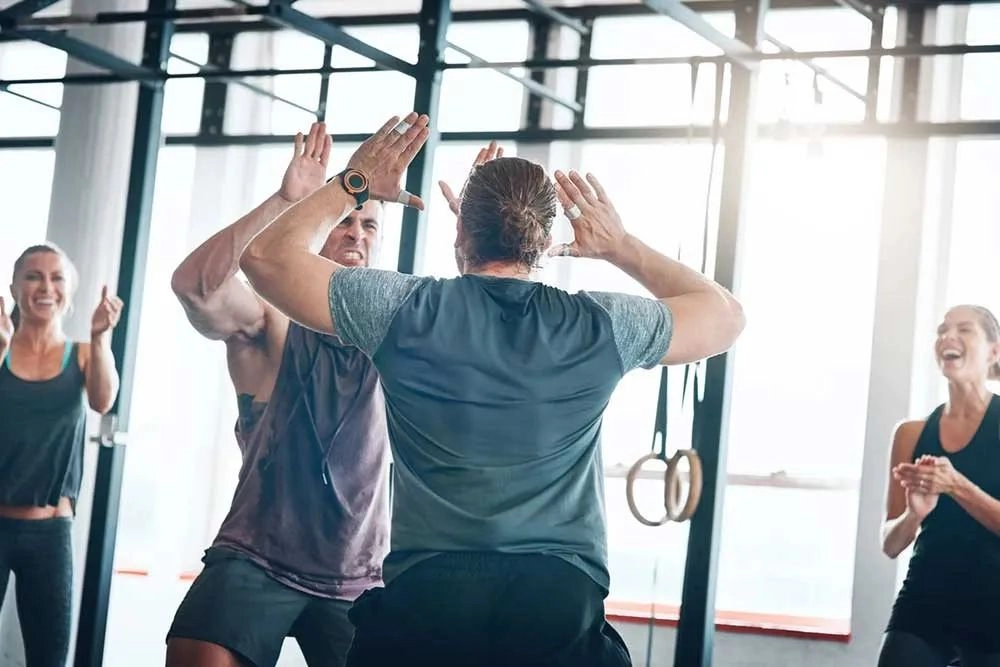 Group of people enjoying unconventional fitness training together, showing humor and motivation in the gym.