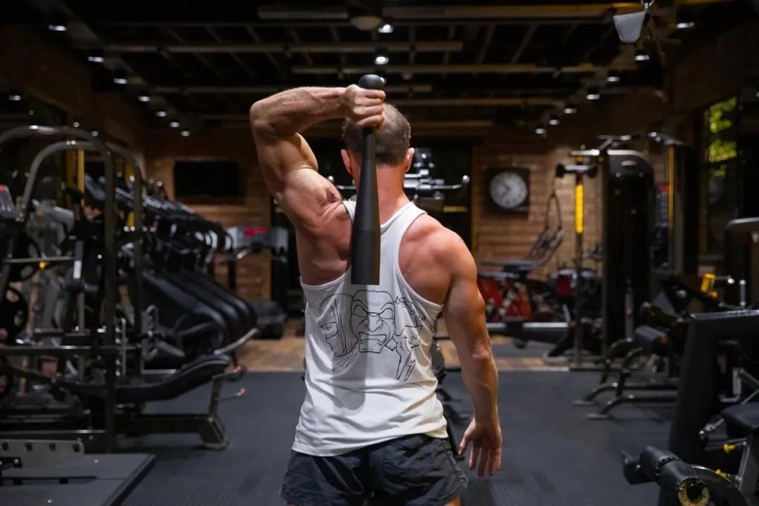 Athlete performing a creative fitness hack using a clubbell to train shoulders and mobility.
