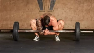 Man demonstrating an unconventional barbell exercise hack to improve grip strength and posture.