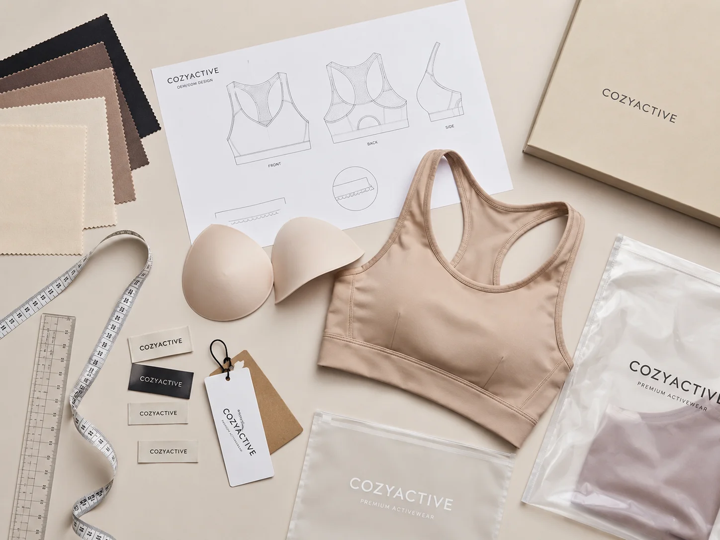 Custom sports bra development workspace with technical drawings, fabric swatches, cups, labels and garment samples